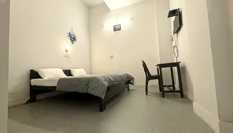 Room 4 bed with grey quilt, desk and wall TV